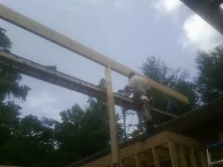 Carpenter setting a ridge beam over a new addition frame — Ice Dam Removal by Roofing Brothers in Doyle
