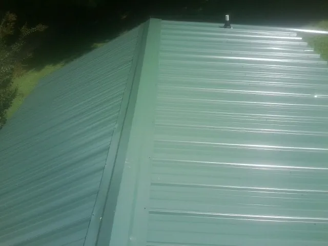 New green metal panels meeting at the ridge of a roof — Flat Roof Repair work by our crew in Doyle