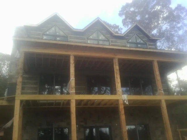 Dormers and porch framing on a large log home under construction — Roof Coating work by our crew in Doyle
