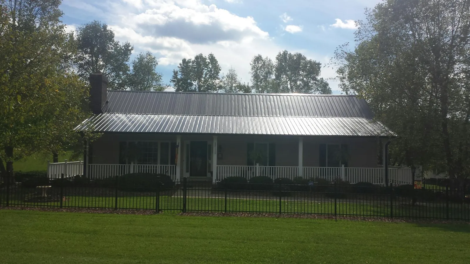 Gray metal roof on a brick ranch with a full width front porch — Gutter Guard Installation work by our crew in Doyle
