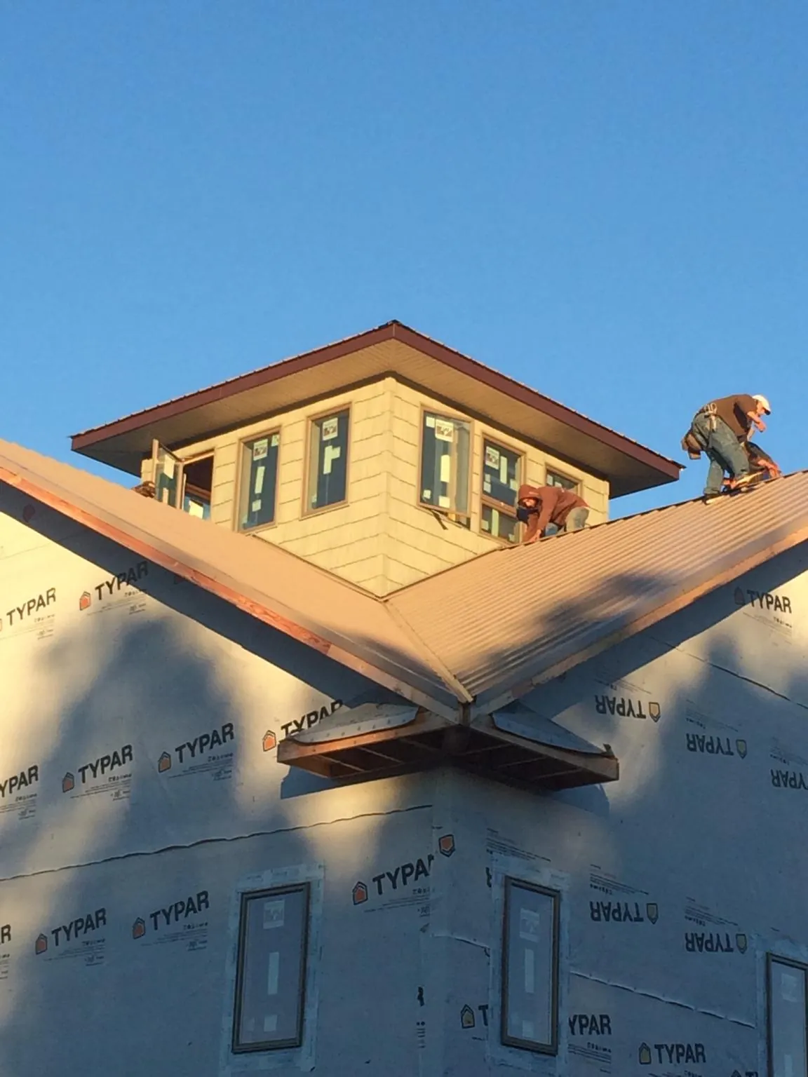 Roofers working around a rooftop cupola on a new metal roof at sunset — Roof Waterproofing in Doyle by Roofing Brothers